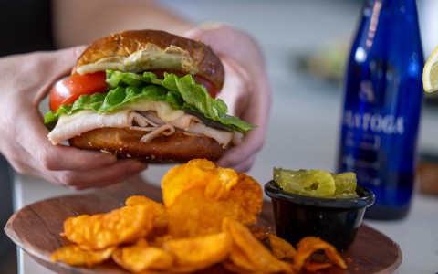 a person holding a sandwich with a side of potato chips