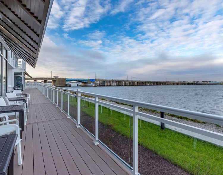 a deck with chairs and a railing overlooking a body of water