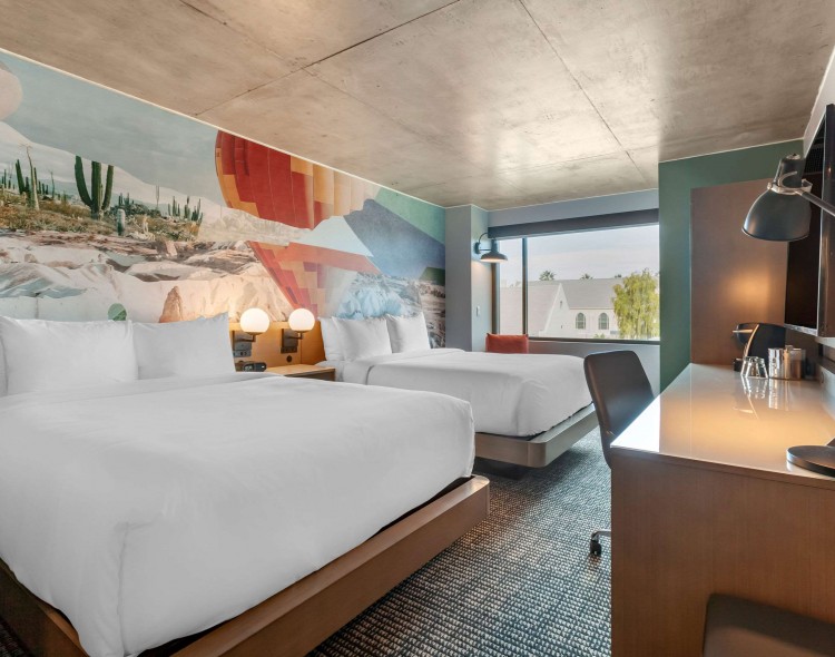 guest room with two beds, a desk, and colorful artwork