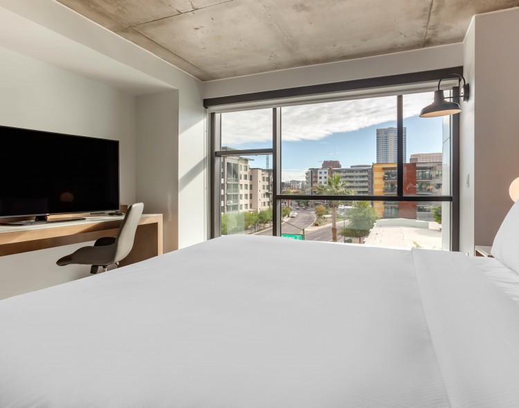 a modern guest room with a white king bed and city views