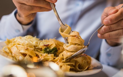a person holding a fork over a plate of pasta