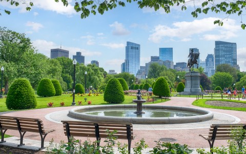 a park with a fountain and a statue in the background