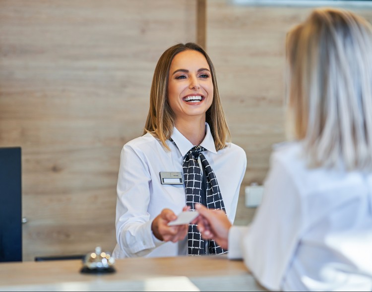 women behind front desk handing a key to guest