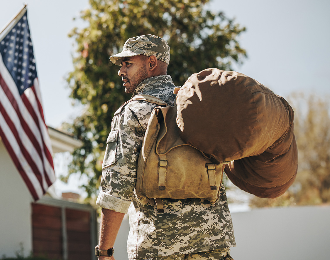 a man in military uniform carrying a large bag