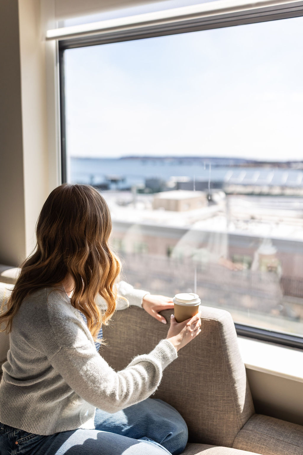 a woman sitting on a couch holding a cup of coffee