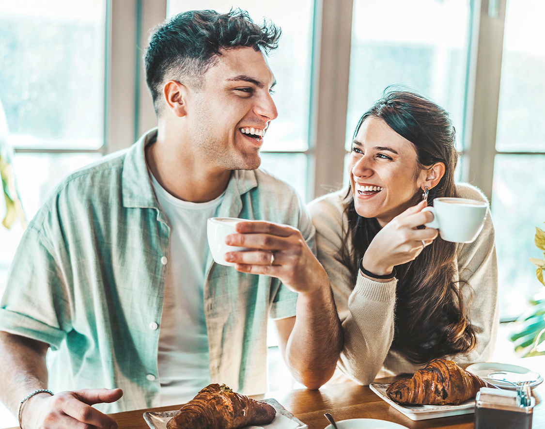 a man and woman sitting at a table with food