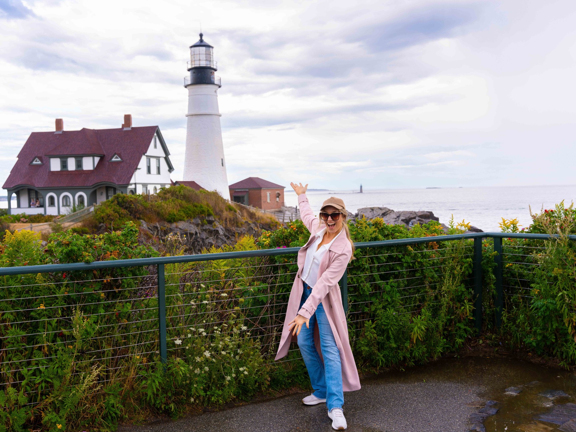 a woman standing next to a fence and a lighthouse