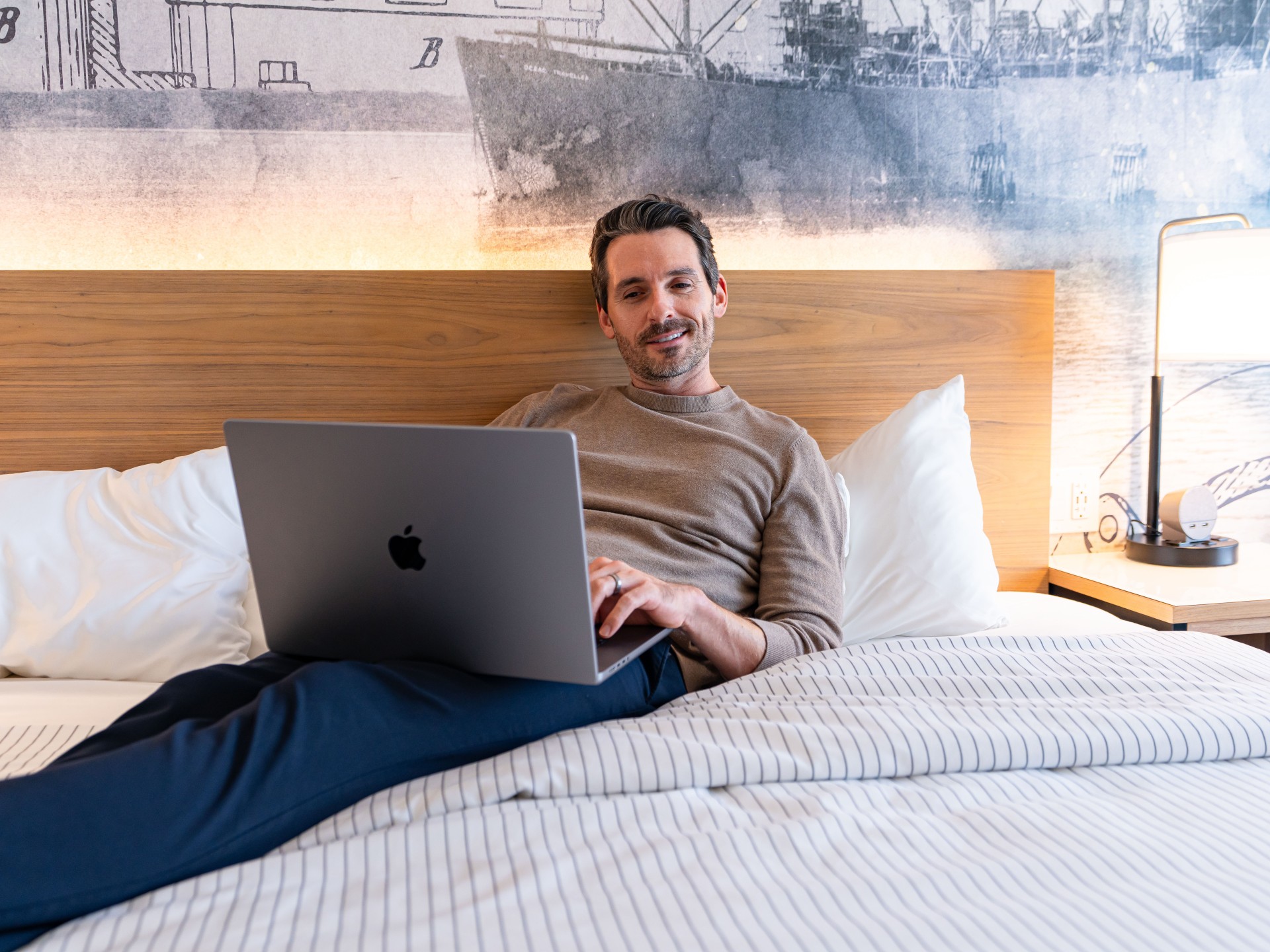 a man sitting on a bed using a laptop
