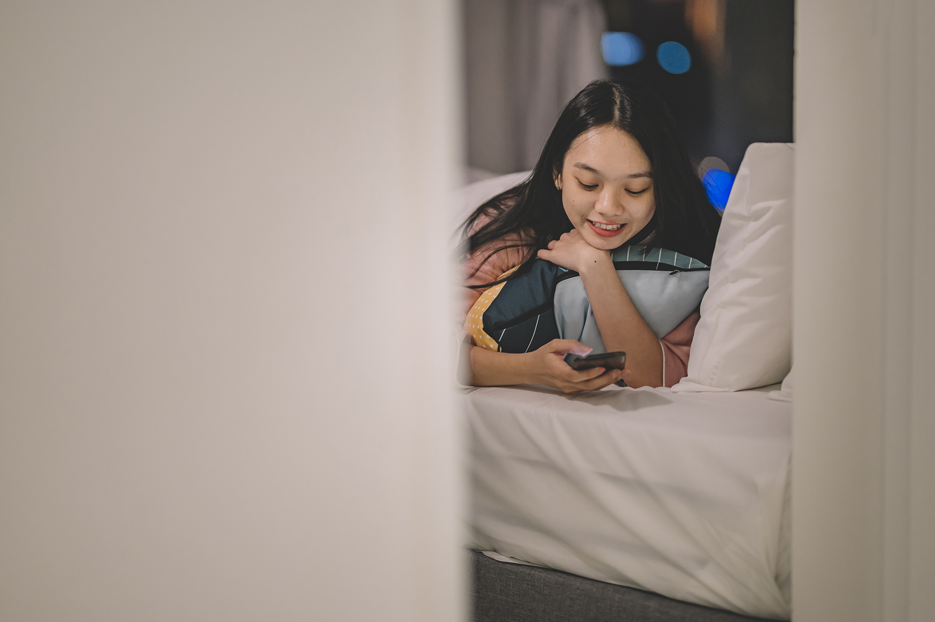 girl laying on bed looking at phone