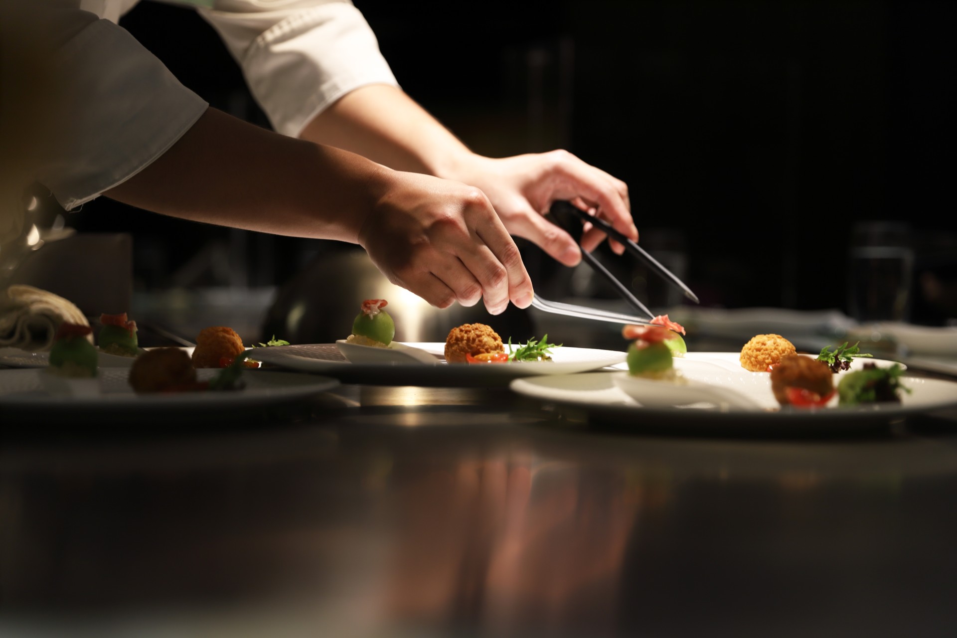 a person's hands holding tongs to a plate of food