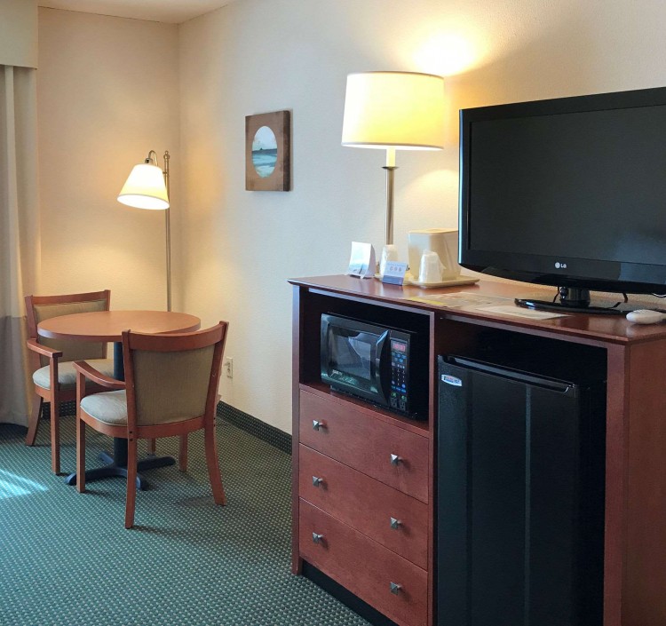table with two chairs, tv, mircowave, and mini fridge in guest room