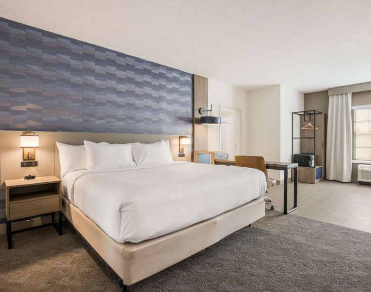 King bed with gray patterned wall and open space next to bed
