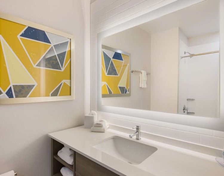bathroom sink and large mirror with yellow and blue geometric image on the wall