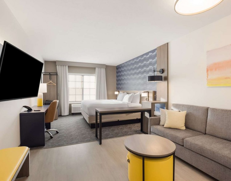 King bed next to gray couch with mounted tv in front of it