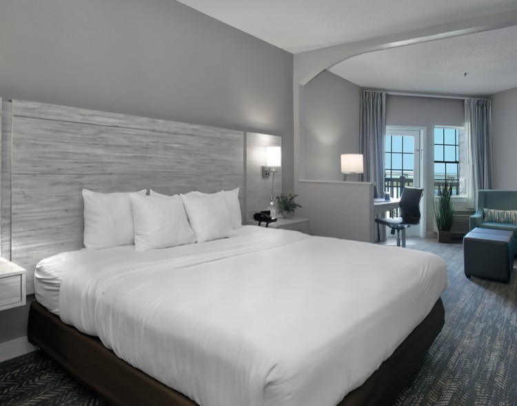 view of a queen bedroom with white sheets and gray accents of the furniture