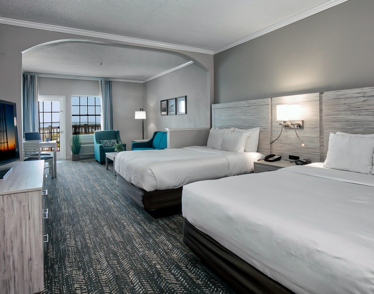two queen beds with a view of the balcony, sitting area, and tv