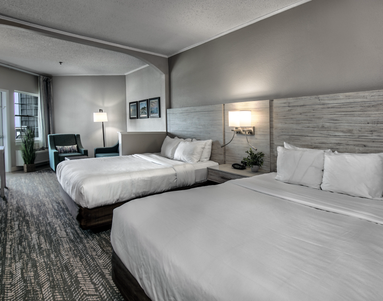 two queen beds in a grey room with a view of the window