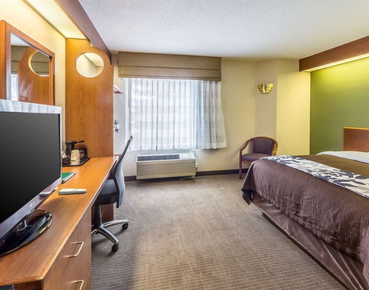 king bed with chair next to bed and tv across from bed