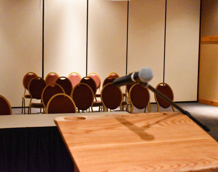 wooden podium with microphone staring out at a row of chairs