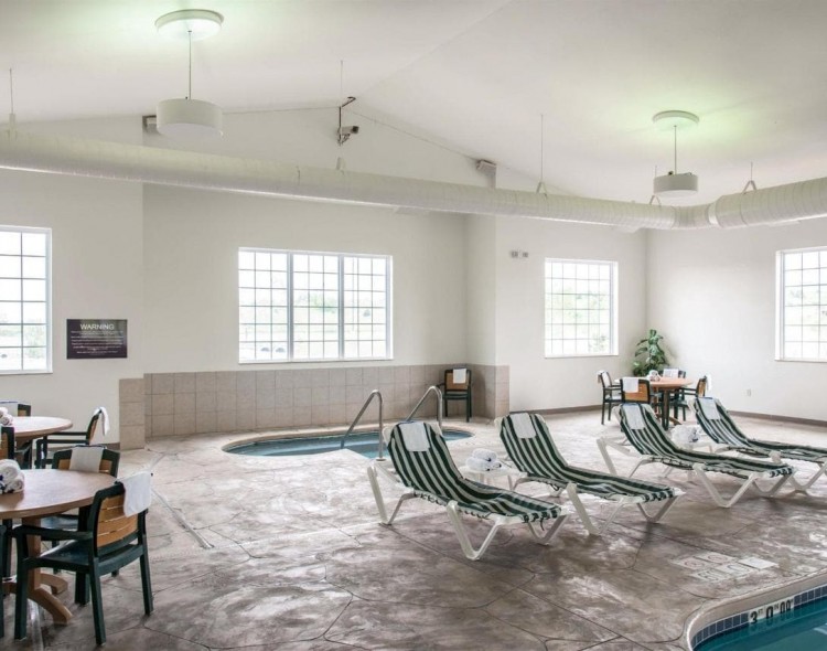 indoor hot tub area with striped lounge chairs in front of it