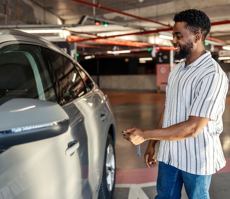 a man standing in a parking lot holding a key