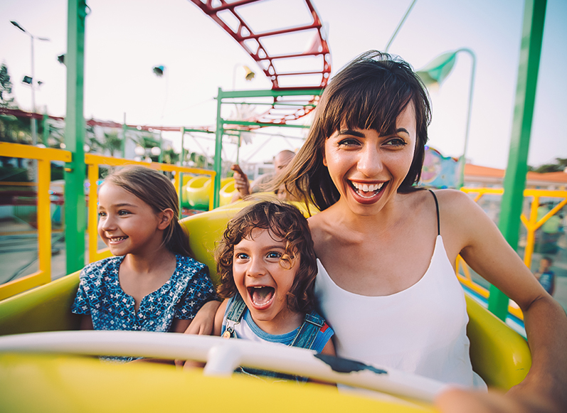 a woman and two children on a roller coaster