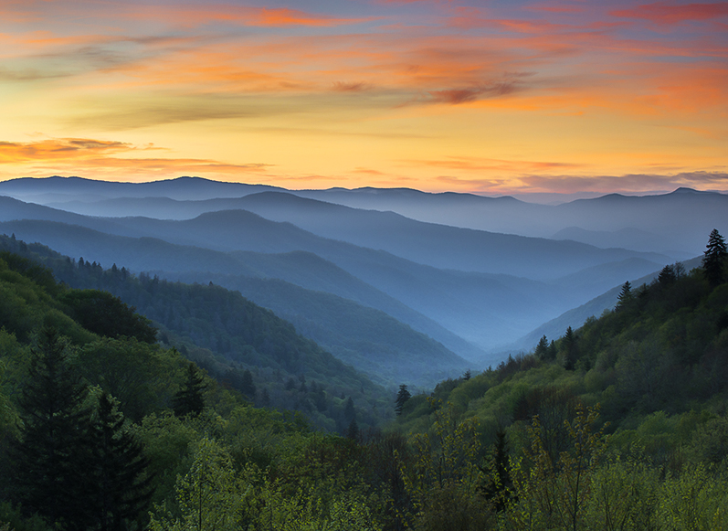 a landscape of mountains with trees and clouds