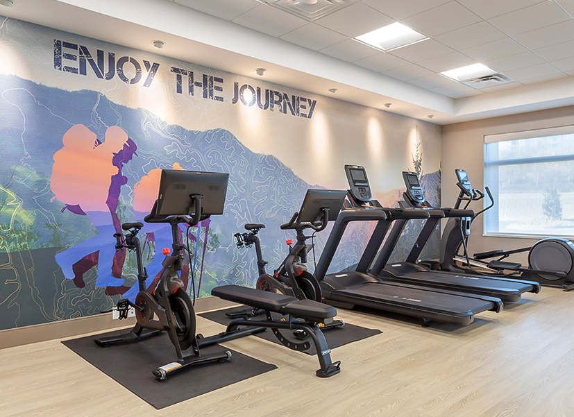 a room with exercise machines and a wall with a poster