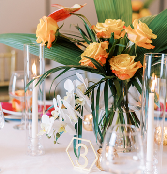 close up of orange roses as a center piece with glasses in the frame