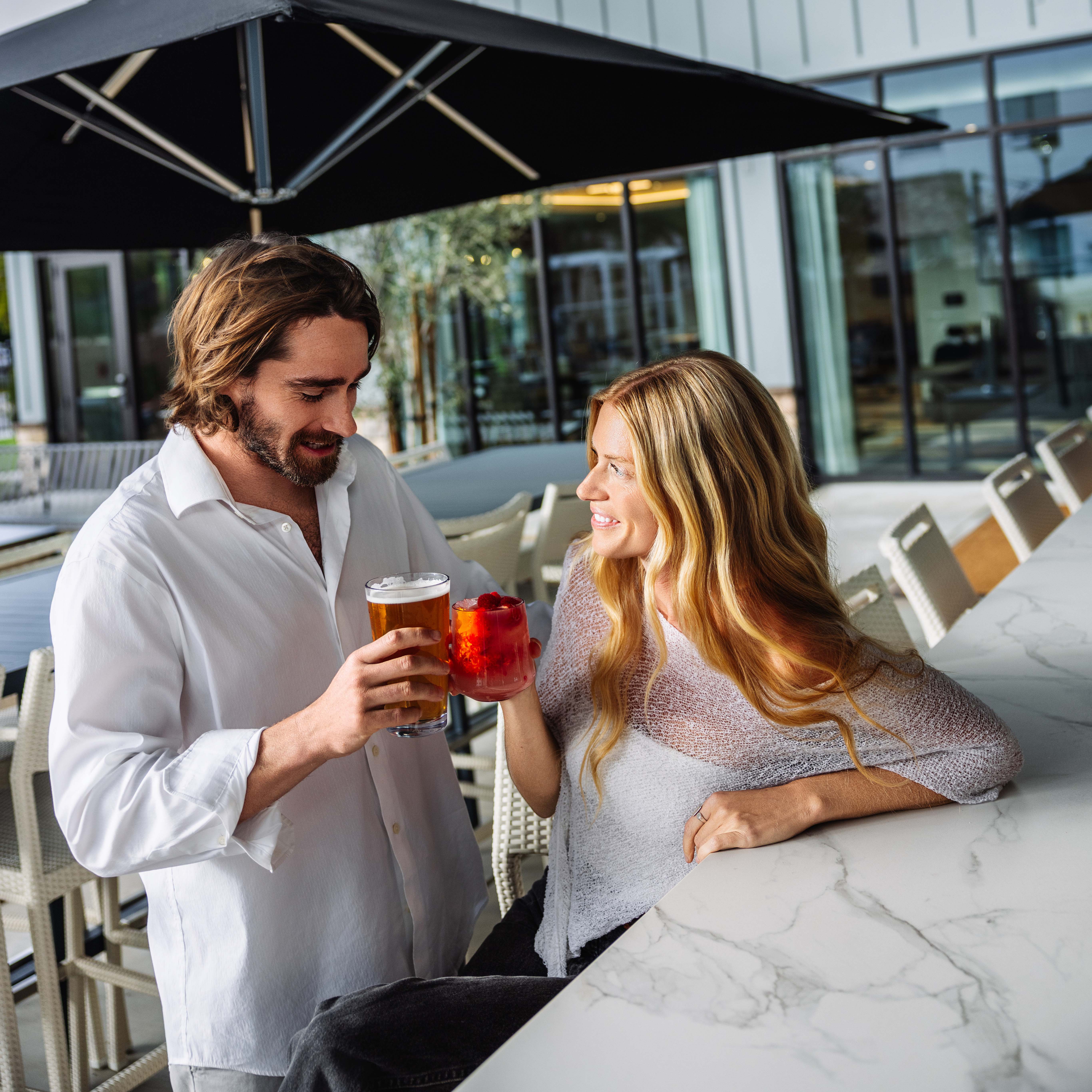 a man and woman holding drinks at a bar