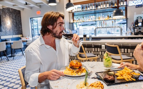 a man drinking wine at a table with food