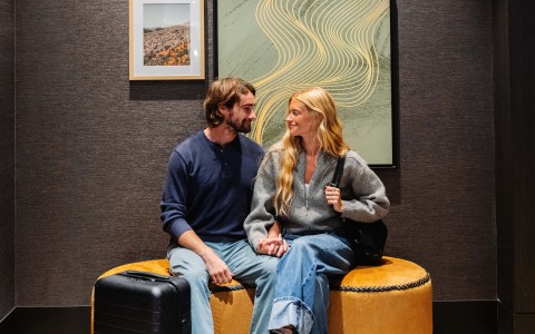 a man and woman sitting on a pouf