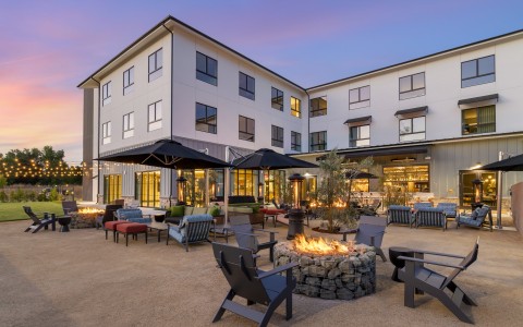 a fire pit with chairs and umbrellas in front of a building