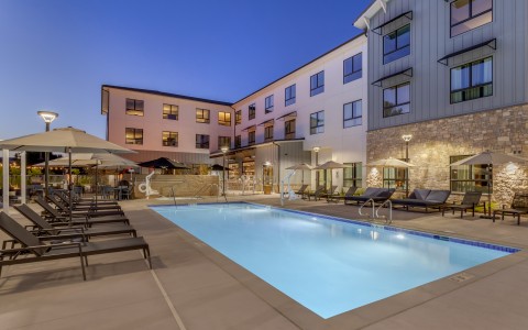 a pool and chairs outside of a building