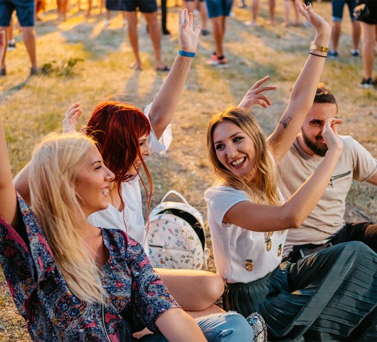 a group of people sitting on the ground with their hands up