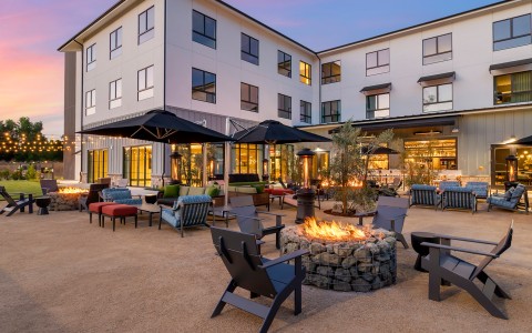 a fire pit with chairs and umbrellas in front of a building