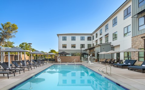 a swimming pool with umbrellas and chairs in front of a building