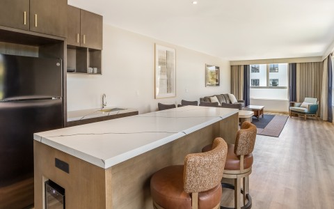 a kitchen and living room with a bar and chairs