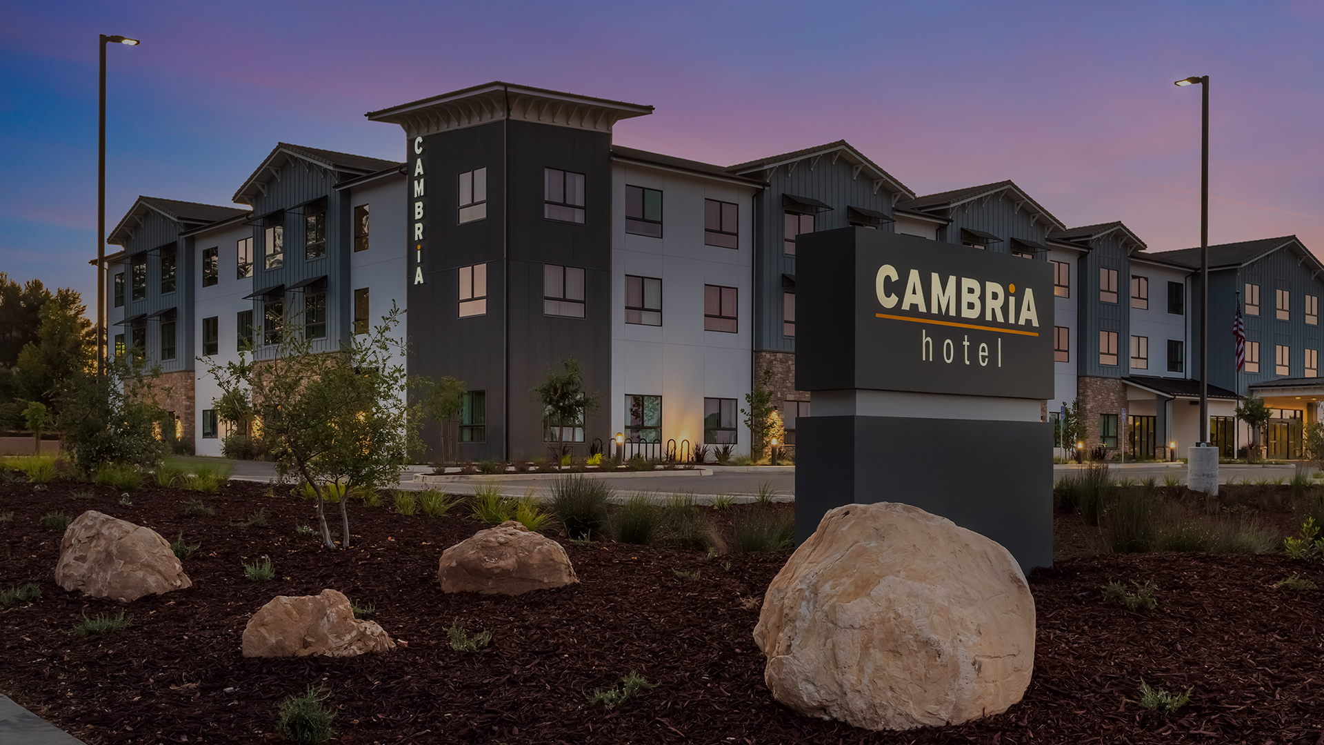 a hotel with a sign and rocks in front of it