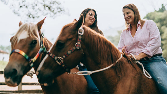 two women riding horses outside