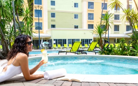 a woman holding a drink by a pool