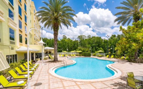 a pool with palm trees and a building