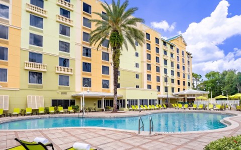 a pool with palm trees and a building