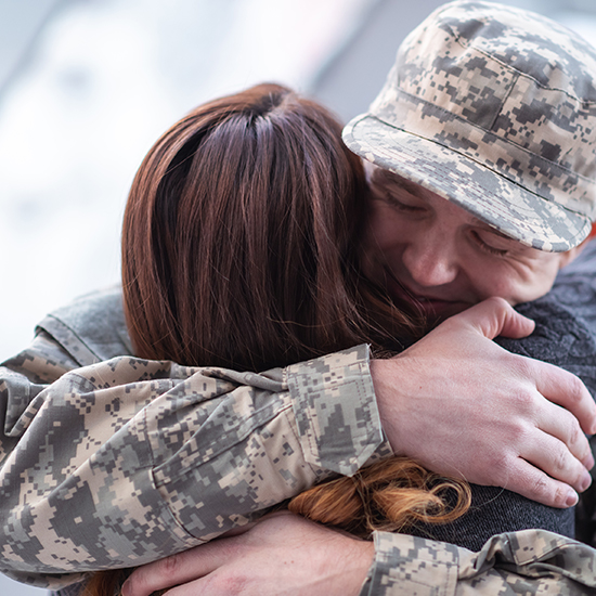 man in military uniform hugging woman