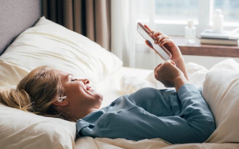 a woman lying in bed with a phone