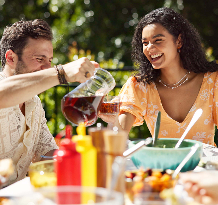 a man and woman sitting at a table with food and drinks