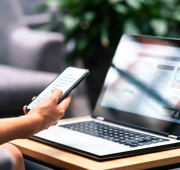 a person holding a phone and using a laptop