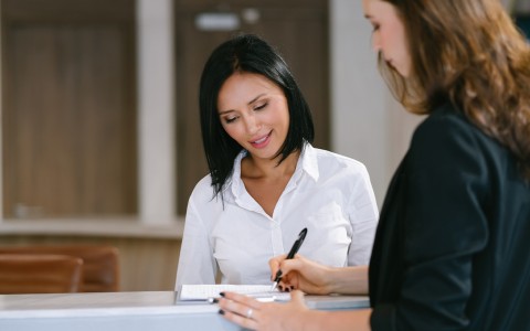 a woman in a white shirt writing on a piece of paper