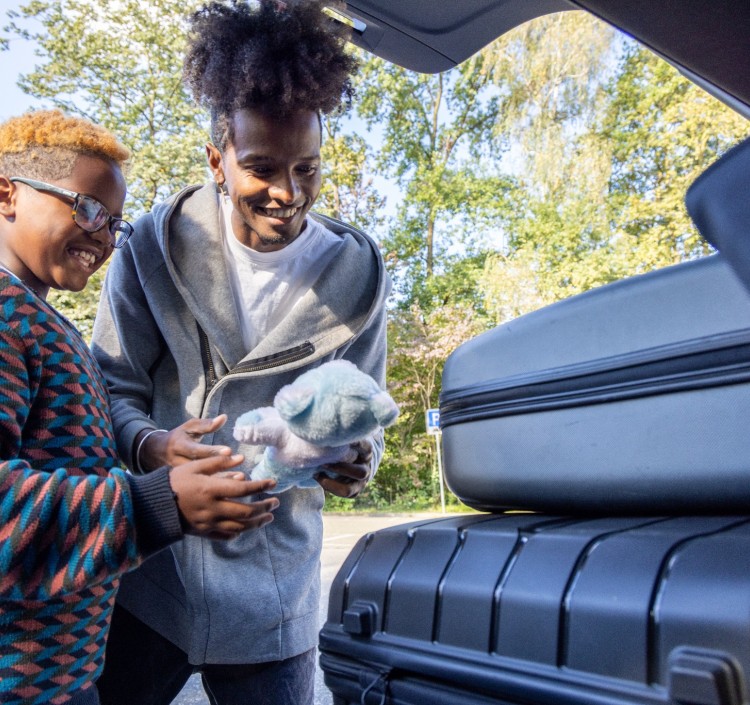 a man and child looking at luggage in the back of a car