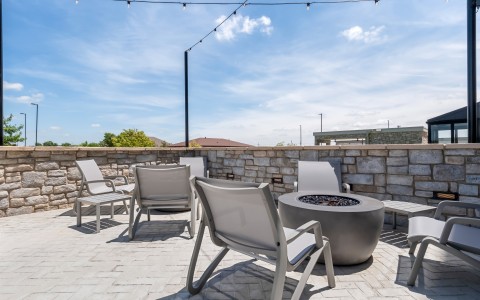 a patio with chairs and a fire pit